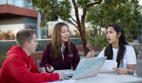 Students sitting together talking with laptop