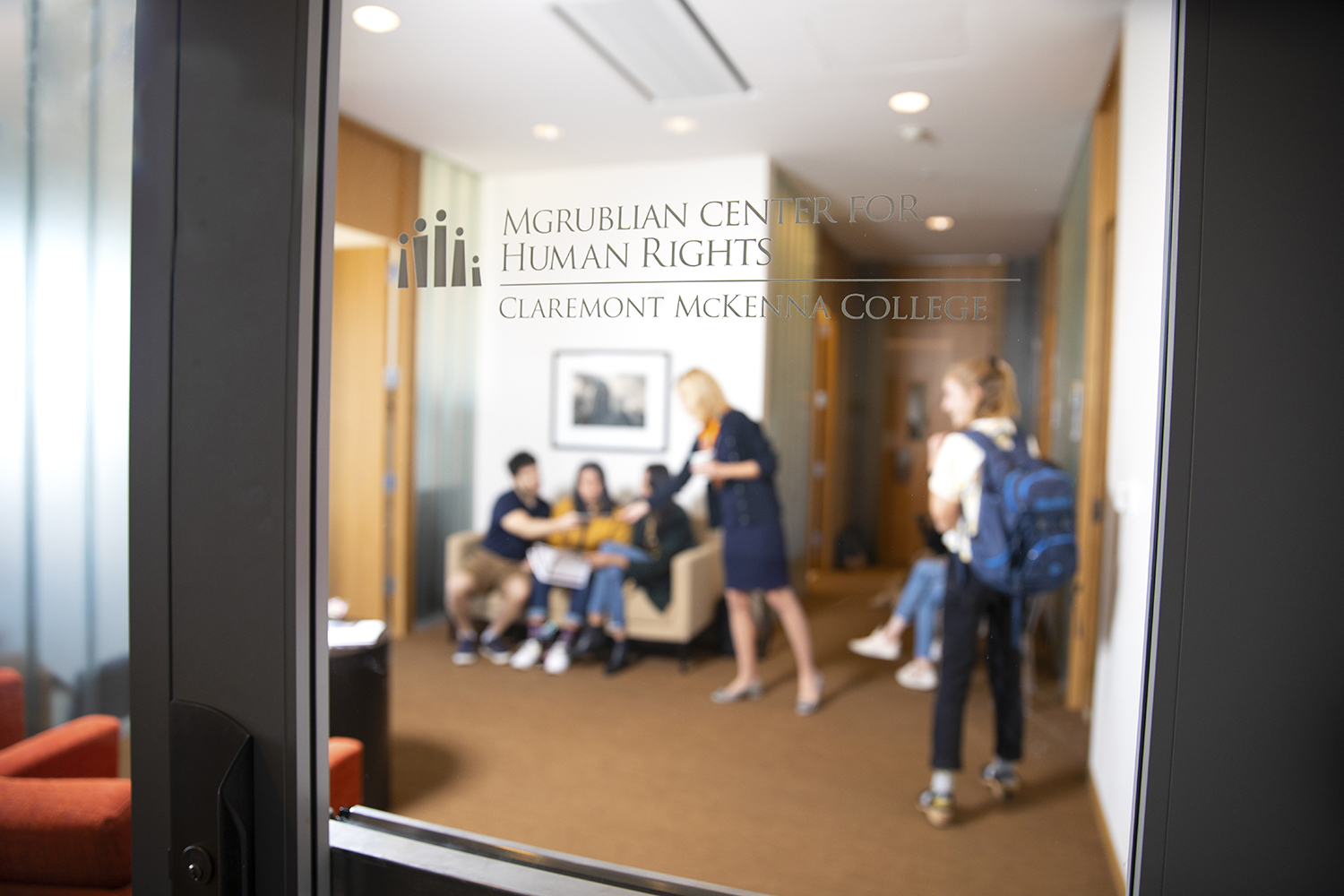 A shot of the Mgrublian Center for Human Rights glass doors shows Wendy greeting students inside.