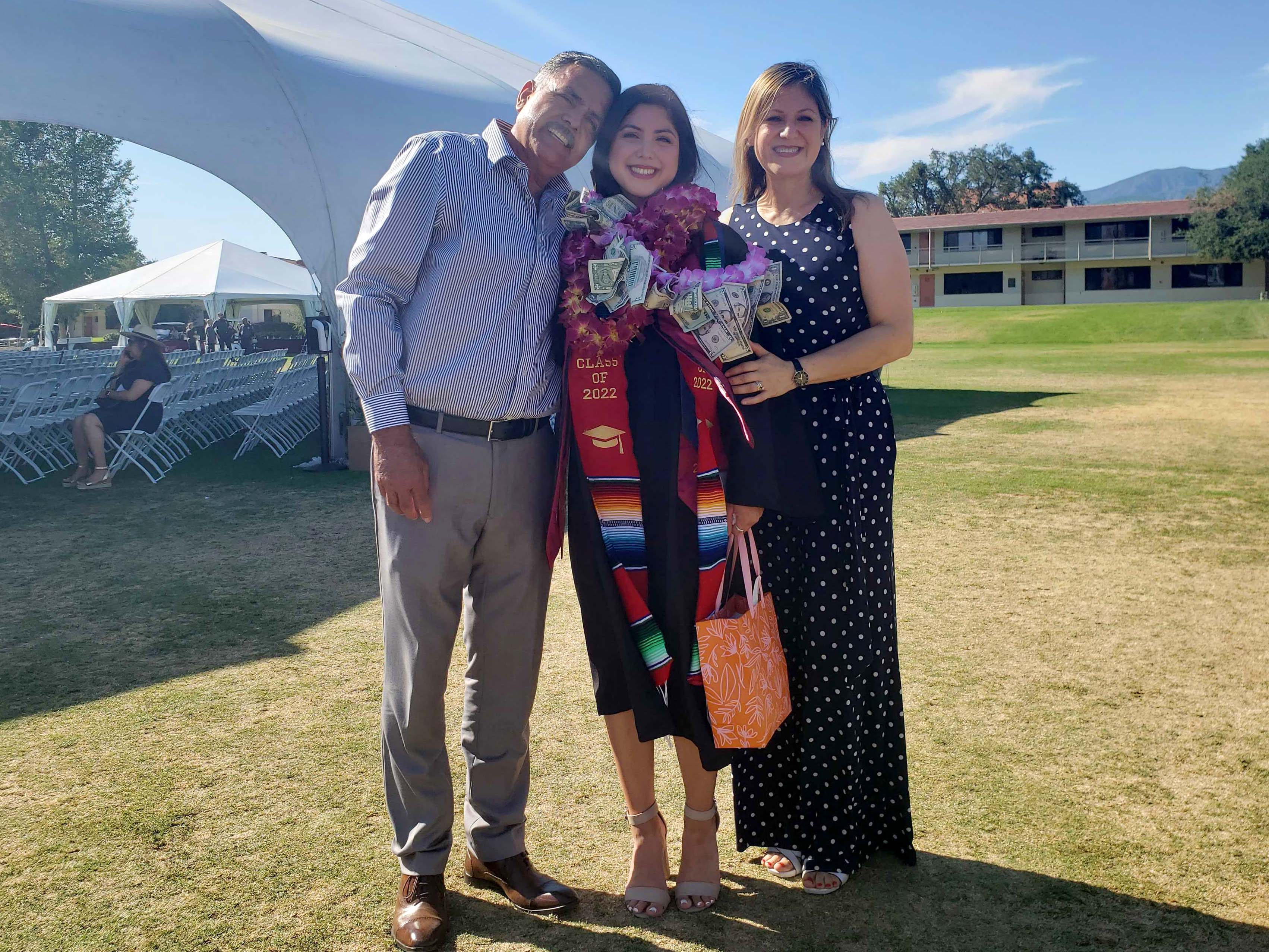 Karina Ramirez ’22 with her parents just outside the giant white tent on CMC's 2022 Commencement.