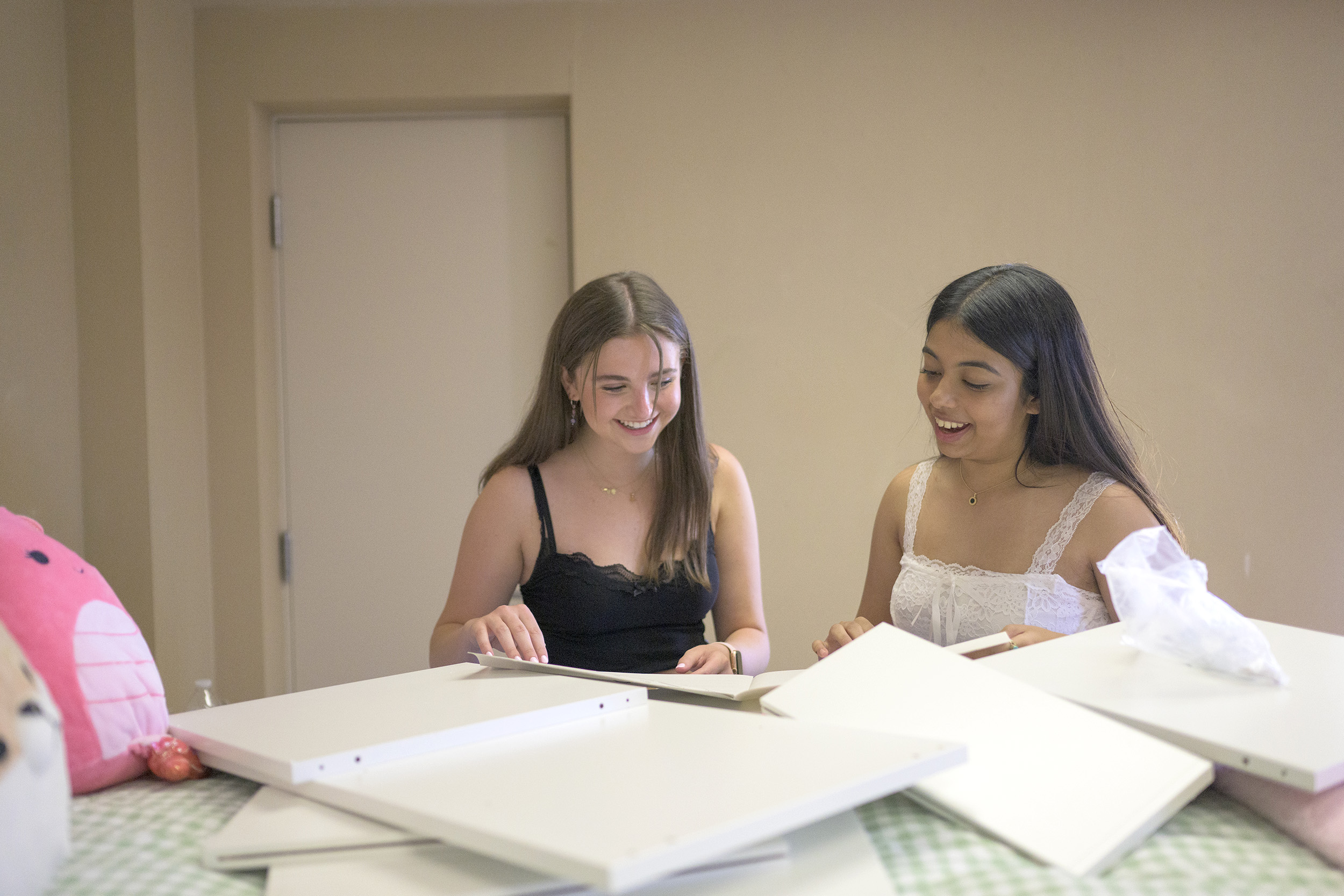 Chloe Ross ’26 (left) and Kiara Jacob ’26 (right) look look over possible dorm decor spread over a bed with plushies.