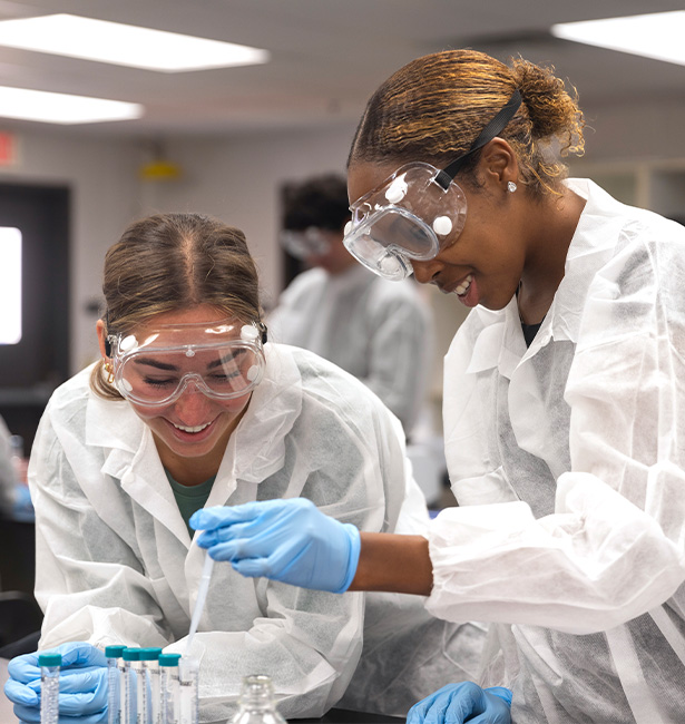Two students working with tubs in a lab.