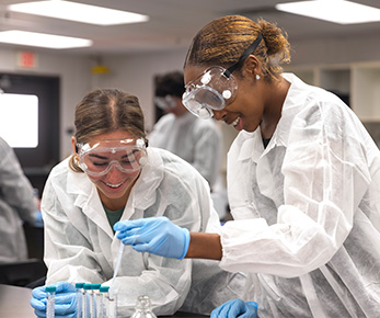 Two students working with tubs in a lab.