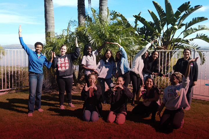 Students posing in front of palm trees.