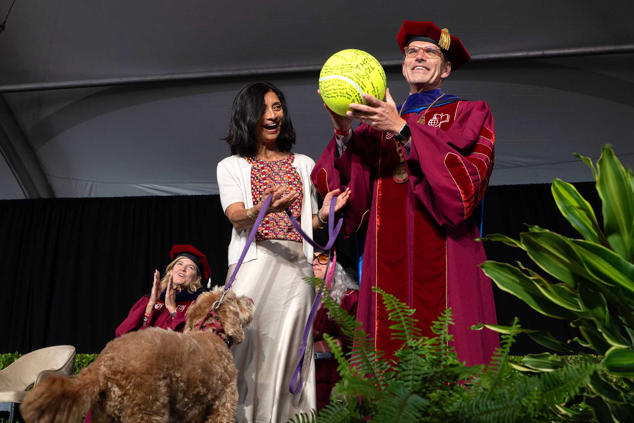 President Chodosh and Priya accepting Theo's award, a giant tennis ball.