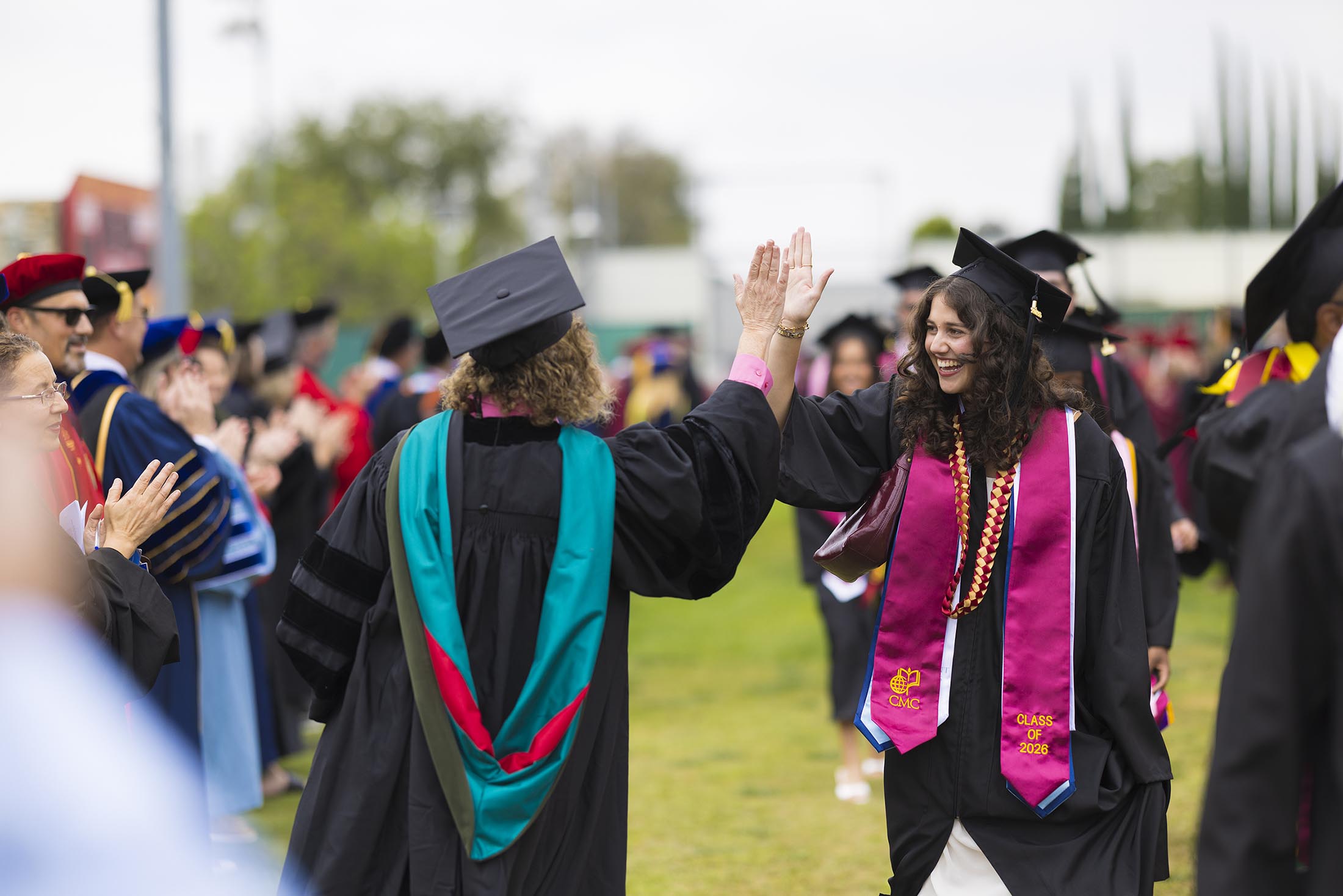 A 2026 graduate high-fives a faculty member. 