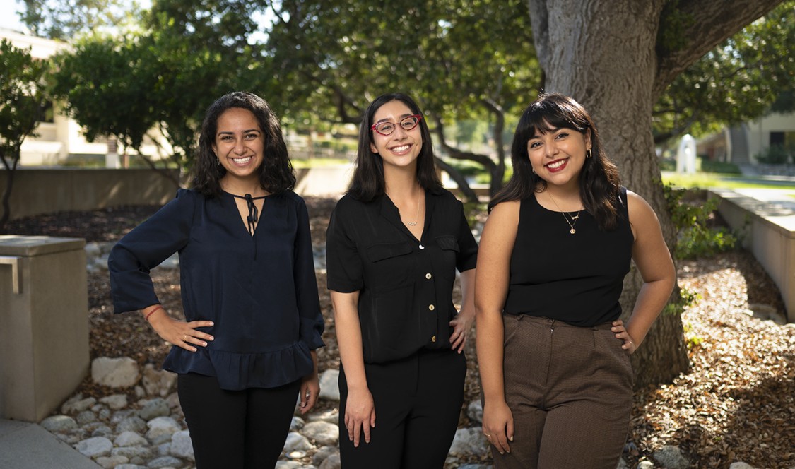 2021 Ath Fellows pose with hands on their hips, lined up prom-style, under the shade of a tree on campus