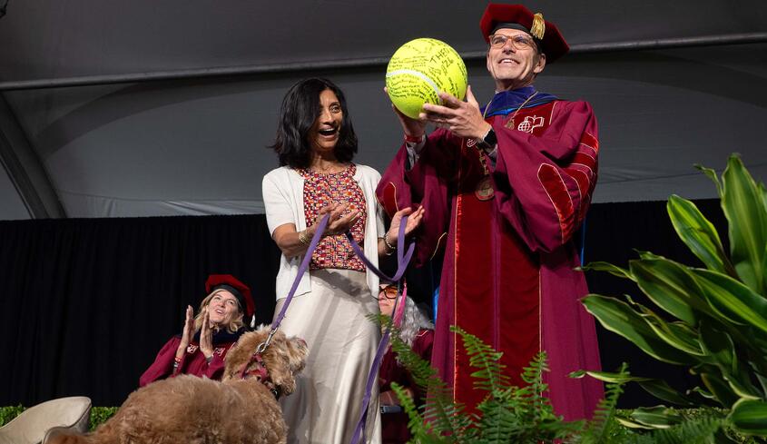 Pres. Chodosh holding large tennis ball with Priya Junnar and Theo