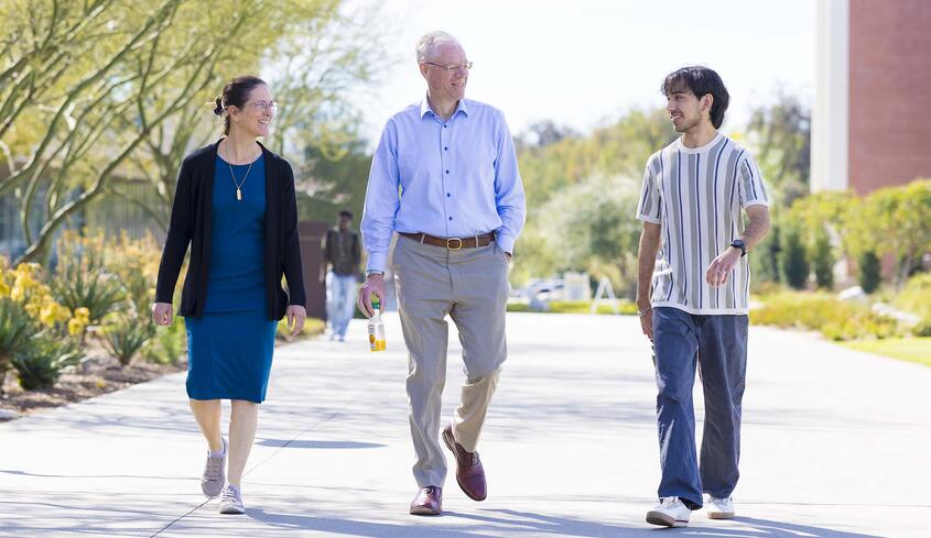 President Will Dudley and wife Dr. Carola Tanna walking with student on campus
