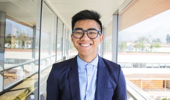 Photograph of a smiling, suited up Jon Joey Telebrico ’23 outside the Keck Center.