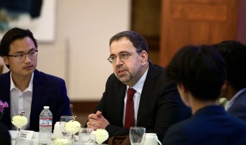 MIT Applied Economics Professor Daron Acemoglu sits at the head table inside the Ath main room.