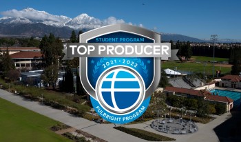 A blue Fulbright Top Producer 2021-2022 badge laid over a down shot of the south west corner of campus (Parents Field, Meet Me in the Middle, softball field, Bauer North and South) with snowcapped San Gabriel mountains in the back.