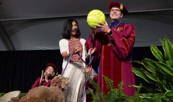 Pres. Chodosh holding large tennis ball with Priya Junnar and Theo