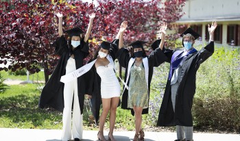 Cheering CMC grads on campus wearing caps and gowns and masks
