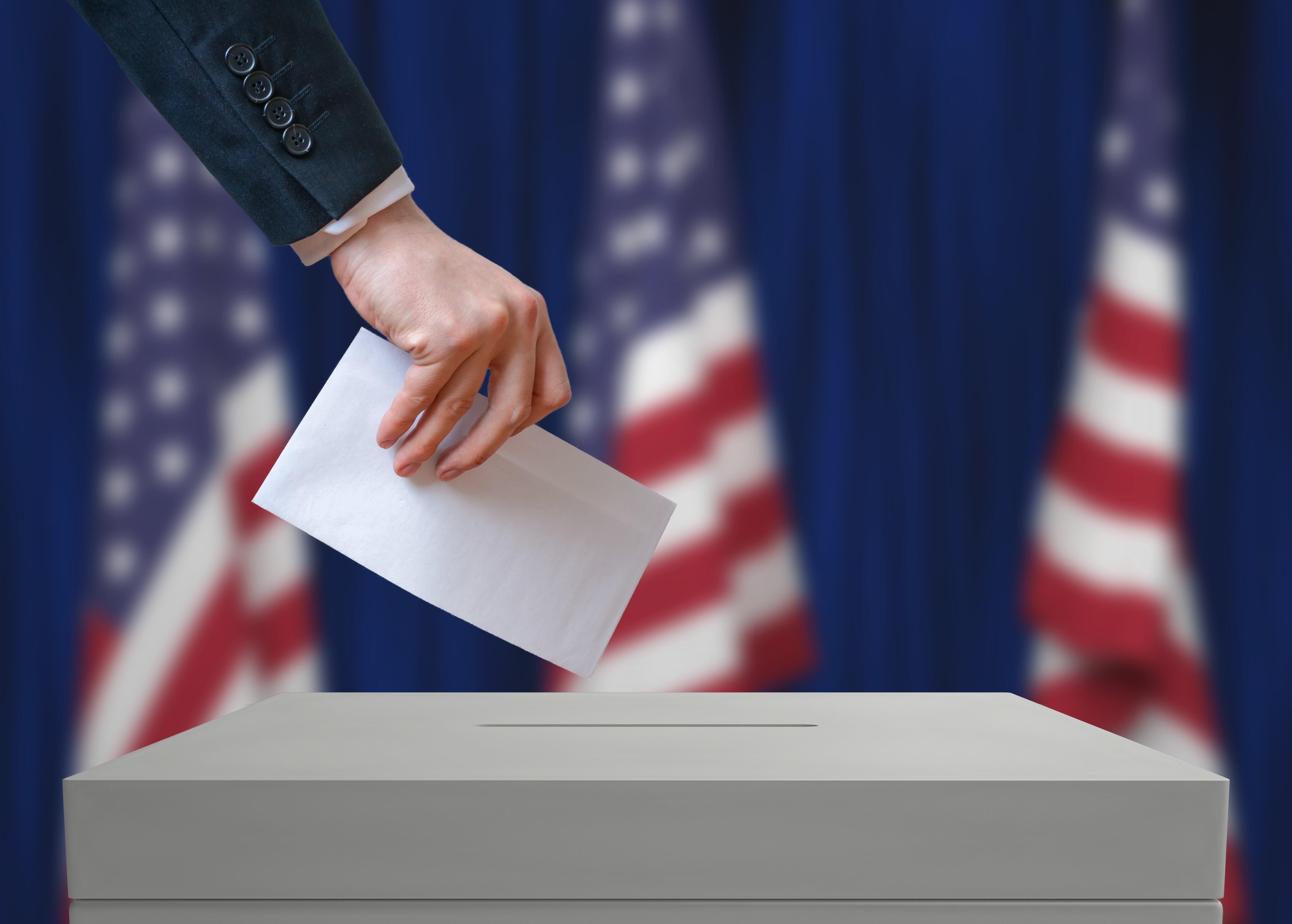Picture of someone dropping a ballot into a box.
