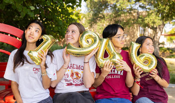 Four students holding 1946 balloons