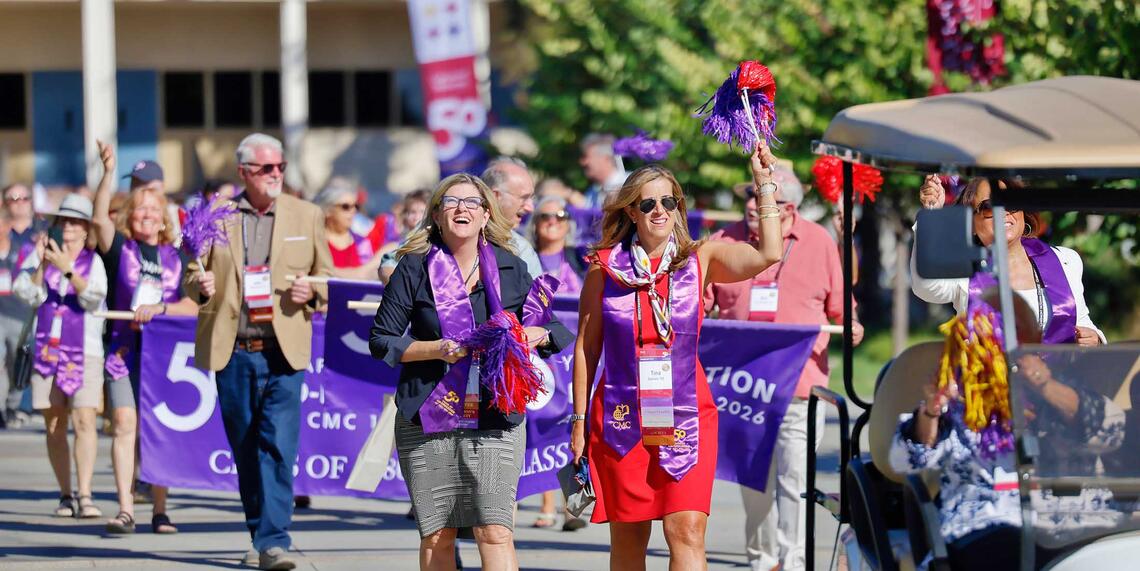 Group of people marching down the campus mall celebrating 50 Years of Co-ed at Impact weekend